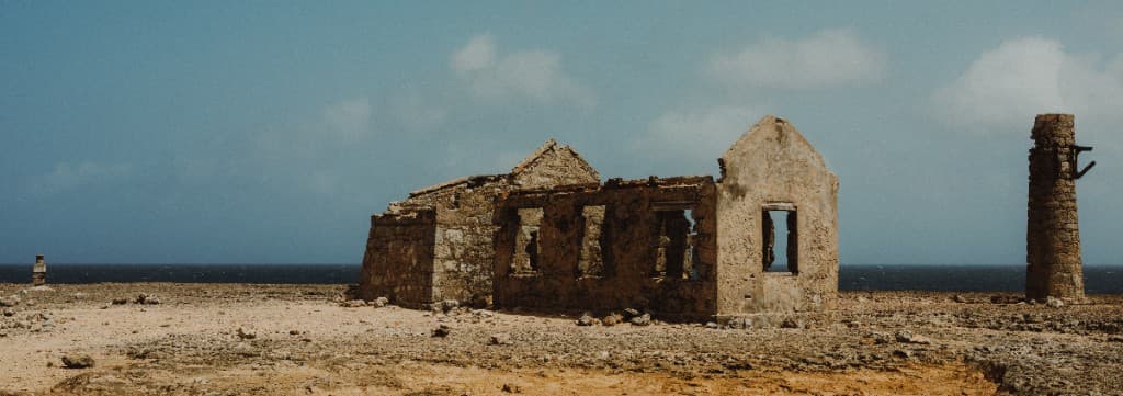 Weathered stone ruins and a freestanding chimney on a rocky coastline